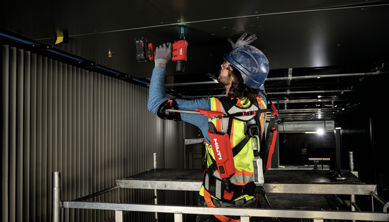 Worker using the RT 6-22 Cordless riveting tool overhead with support from the EXO-S Shoulder exoskeleton
