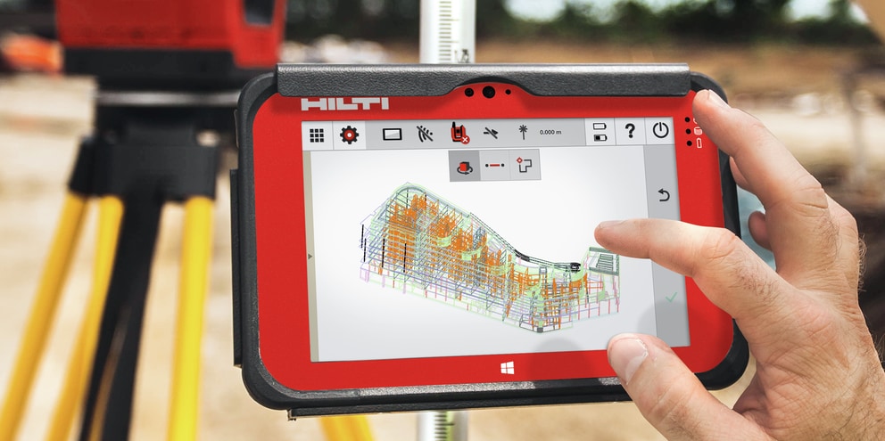 Two workers onsite using a Total Station layout tool and BIM-ready tablet to position MEP supports