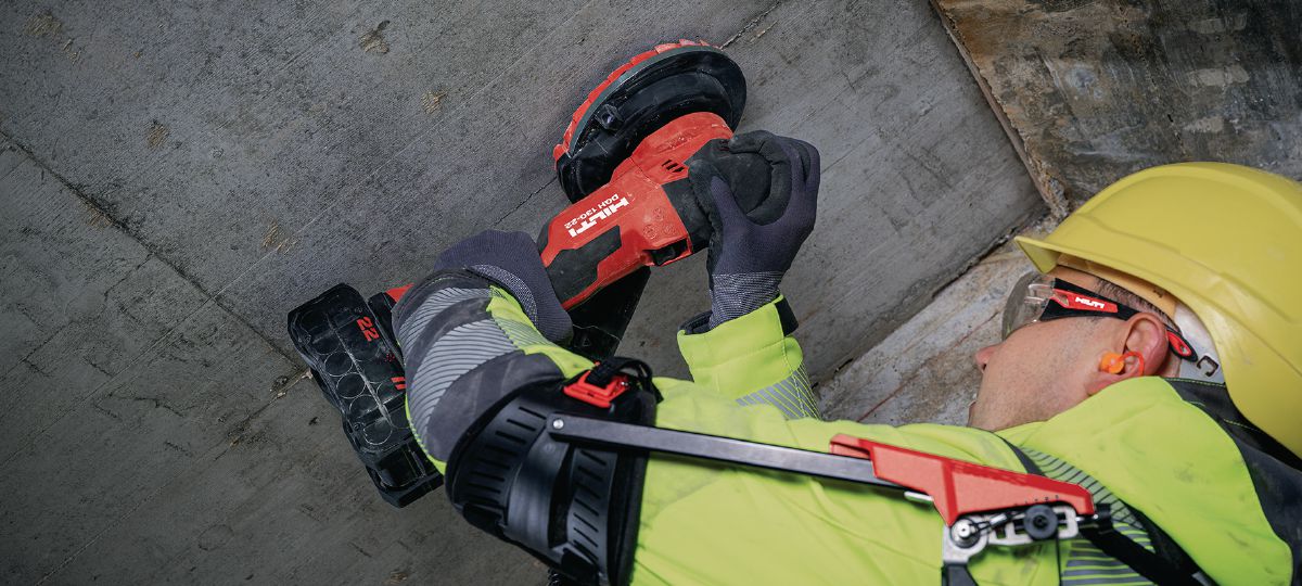 Application picture of cordless concrete grinder DGH 130-22 for grinding and finishing work on concrete with Exoskeleton and vacuum system.