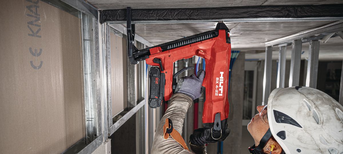 Cropped application picture of a construction worker doing a roof overhead application using the BX 4-22 with support leg mounted and the B22-85 battery