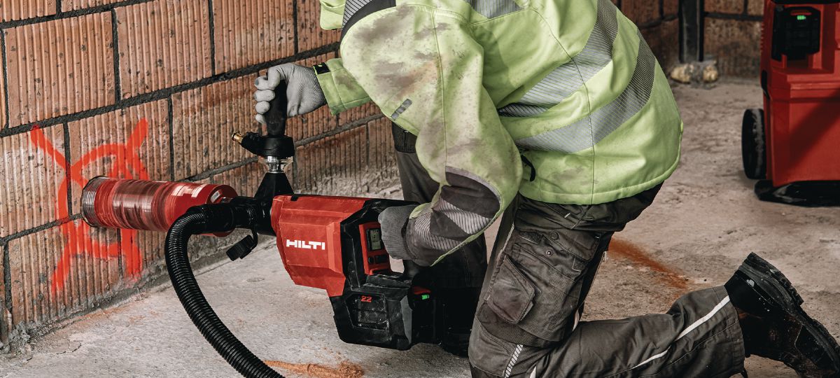 Cropped application picture of the cordless core drill DD 150-U-22 with the SPX A speed core bit and attached to the cordless vacuum cleaner VC 4X-22. Hand-held dry coring in masonry.