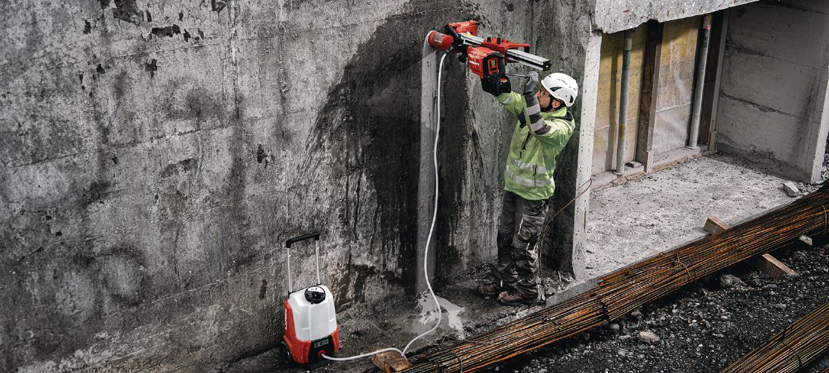 Cropped application picture of the cordless core drill DD 150-U-22 with the SPX A speed core bit and attached to a drill stand and water pump DWP 15-22. Rig-based wet coring in concrete.