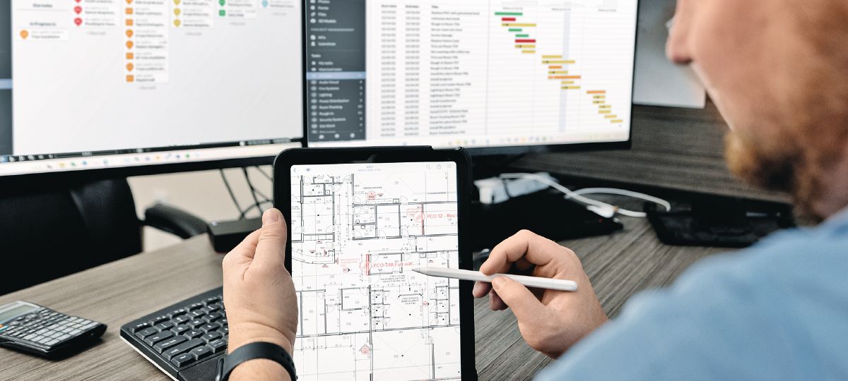 Cropped picture of a project manager sitting at a desk in the office using Fieldwire on computer.